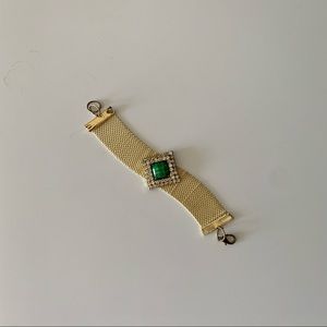 Gold tone bracelet with green stone in center.
